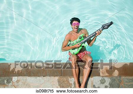 Stock Photography - Man in pool with inflatable guitar. Fotosearch