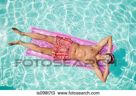 Stock Image - Man on inflatable mattress in pool. Fotosearch