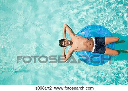 Stock Image - Man on inflatable ring in pool. Fotosearch