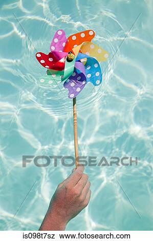 Stock Photo - Person holding pinwheel in swimming pool. Fotosearch