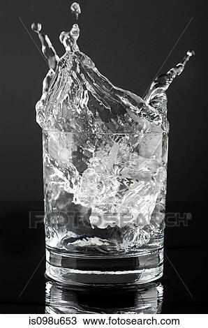 Stock Image - Ice cube splashing in a tumbler of gin and tonic. Fotosearch