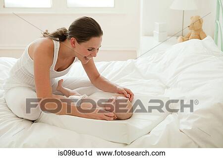 Stock Image - Mother with baby son on changing mat. Fotosearch
