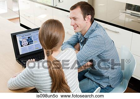 Young couple looking at insurance on laptop View Large Photo Image Picture - Young couple looking at insurance on laptop. Fotosearch