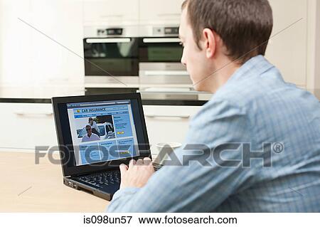 Young man looking at car insurance on laptop View Large Photo Image Stock Photo - Young man looking at car insurance on laptop. Fotosearch