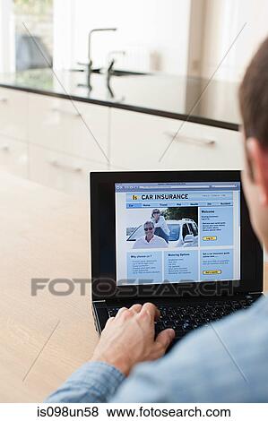 Young man looking at car insurance on laptop View Large Photo Image Stock Photo - Young man looking at car insurance on laptop. Fotosearch