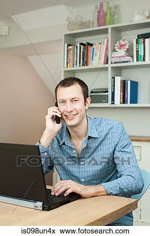 Stock Photo - Young man using laptop and phone. Fotosearch