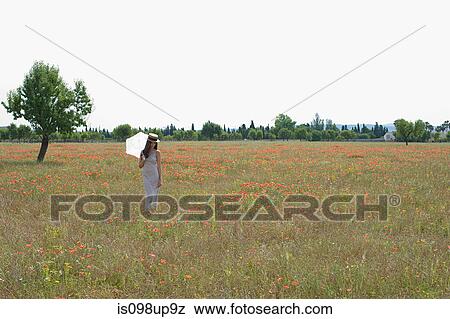 Young woman standing in poppy field with white parasol View Large Photo Image Stock Photo - Young woman standing in poppy field with white parasol. Fotosearch