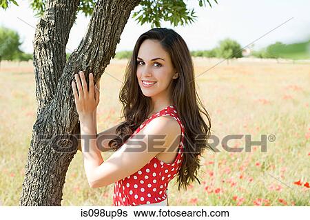 Young woman touching tree in poppy field View Large Photo Image Stock Photograph - Young woman touching tree in poppy field. Fotosearch