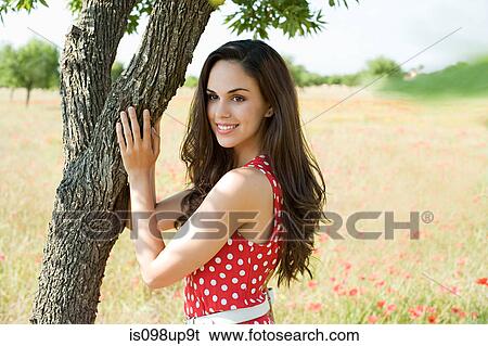 Young woman touching tree in poppy field View Large Photo Image Stock Photograph - Young woman touching tree in poppy field. Fotosearch