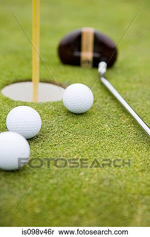 Stock Photography - Golf balls and golf hole, close up. Fotosearch
