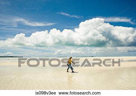 Stock Image - Man walking along beach. Fotosearch