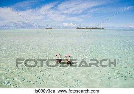Stock Image - Mid adult couple snorkeling and looking at fish. Fotosearch