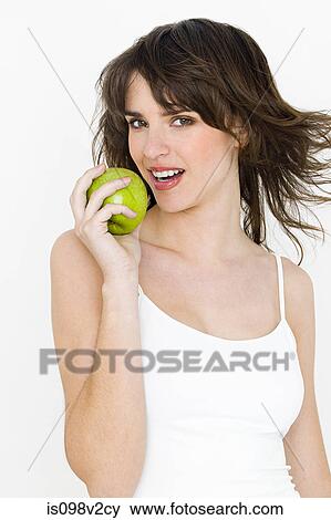 Stock Photo - Portrait of young brunette woman eating apple. Fotosearch