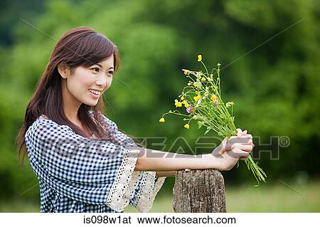 Stock Photograph - Woman holding bunch of wild flowers. Fotosearch