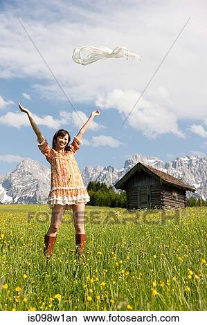 Picture - Woman throwing scarf in meadow with Bavarian Alps in background, Germany. Fotosearch