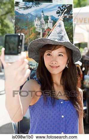 Stock Image - Woman wearing Bavarian hat photographing self. Fotosearch