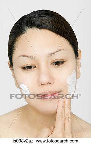 Stock Photo - Young woman applying face cream. Fotosearch