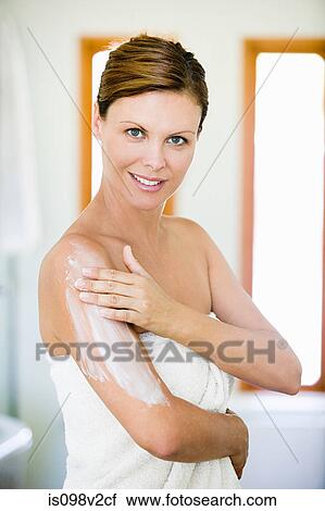 Stock Image - Young woman applying moisturiser. Fotosearch