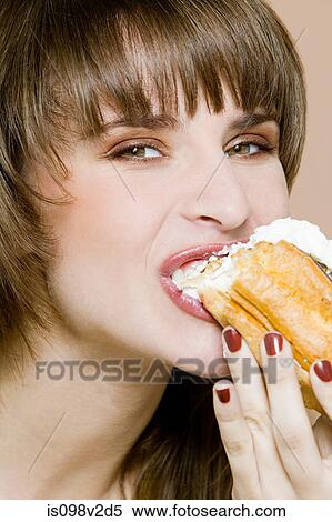 Stock Photography - Young woman biting chocolate eclair. Fotosearch