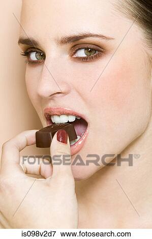Young woman biting chocolate View Large Photo Image Stock Photo - Young woman biting chocolate. Fotosearch