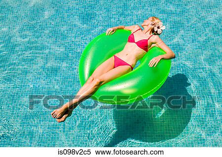 Young woman floating on green inflatable ring in swimming pool View Large Photo Image Stock Photography - Young woman floating on green inflatable ring in swimming pool. Fotosearch