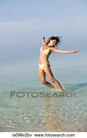 Stock Photo - Young woman jumping in sea. Fotosearch