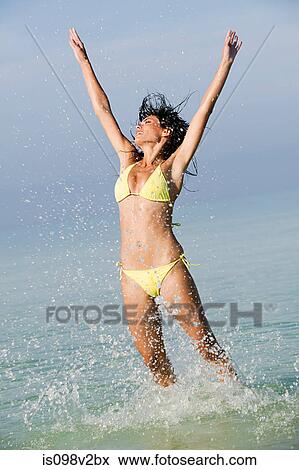 Stock Photo - Young woman jumping in sea. Fotosearch