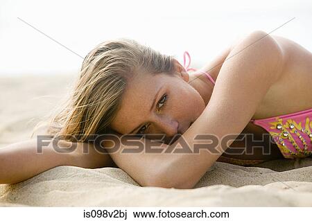 Stock Image - Young woman lying on sand on vacation. Fotosearch