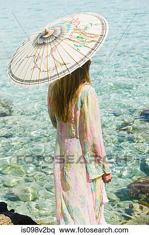 Stock Photography - Young woman on vacation with parasol. Fotosearch