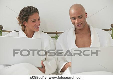 Couple in bed with laptops View Large Photo Image Stock Photo - Couple in bed with laptops. Fotosearch