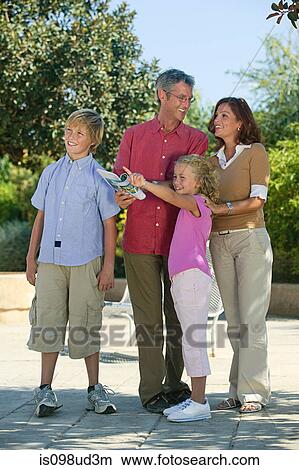 Picture - Family looking at guidebook and pointing. Fotosearch