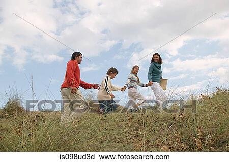 Stock Image - Family walking hand in hand over dune. Fotosearch