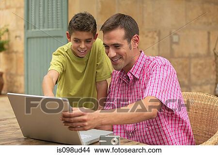 Father and son looking at laptop outdoors View Large Photo Image Picture - Father and son looking at laptop outdoors. Fotosearch