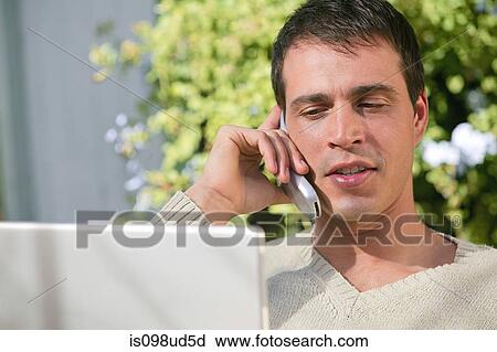 Stock Image - Man on cellphone with laptop. Fotosearch
