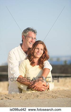 Mature couple outdoors, man with arms around woman View Large Photo Image Stock Image - Mature couple outdoors, man with arms around woman. Fotosearch