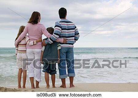 Rear view of family standing by the sea View Large Photo Image Stock Image - Rear view of family standing by the sea. Fotosearch