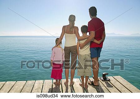 Rear view of family standing on jetty View Large Photo Image Picture - Rear view of family standing on jetty. Fotosearch