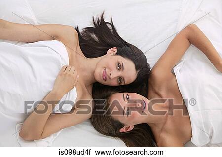 Two young women lying in bed, overhead view View Large Photo Image Stock Image - Two young women lying in bed, overhead view. Fotosearch