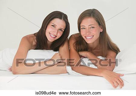 Stock Image - Two young women on a bed. Fotosearch
