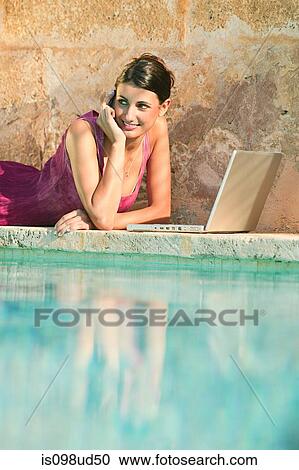 Woman lying by swimming pool with laptop View Large Photo Image Stock Image - Woman lying by swimming pool with laptop. Fotosearch