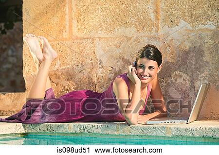 Woman lying by swimming pool with laptop View Large Photo Image Stock Image - Woman lying by swimming pool with laptop. Fotosearch