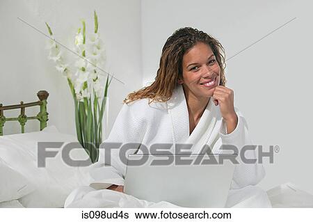 Woman sitting on bed with laptop View Large Photo Image Stock Photograph - Woman sitting on bed with laptop. Fotosearch