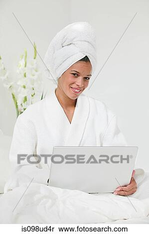 Stock Photography - Woman with laptop and hair wrapped in towel. Fotosearch