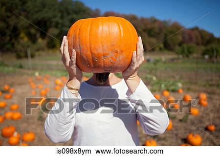 Person holding a pumpkin in front of face View Large Photo Image Picture - Person holding a pumpkin in front of face. Fotosearch