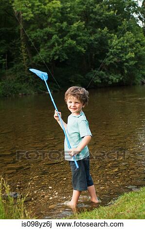 Boy holding fishing net by river View Large Photo Image Stock Image - Boy holding fishing net by river. Fotosearch