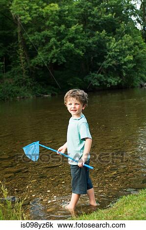 Boy holding fishing net by river View Large Photo Image Stock Image - Boy holding fishing net by river. Fotosearch