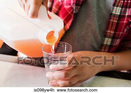 Stock Image - Boy pouring glass of juice. Fotosearch