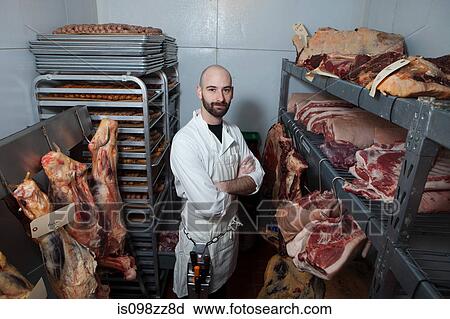 Stock Image - Butcher in meat storage area. Fotosearch