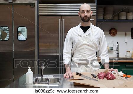 Stock Image - Butcher preparing beef tenderloin. Fotosearch