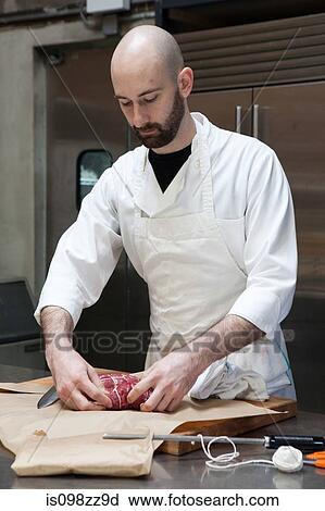 Stock Image - Butcher preparing beef tenderloin. Fotosearch